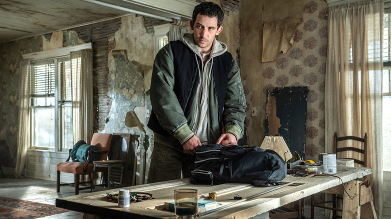 Josh O'Connor as the main character standing in front of a table and packing a backpack in Disclosure Day