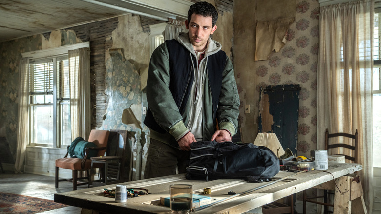 Josh O'Connor as the main character standing at a table and packing a backpack in Disclosure Day