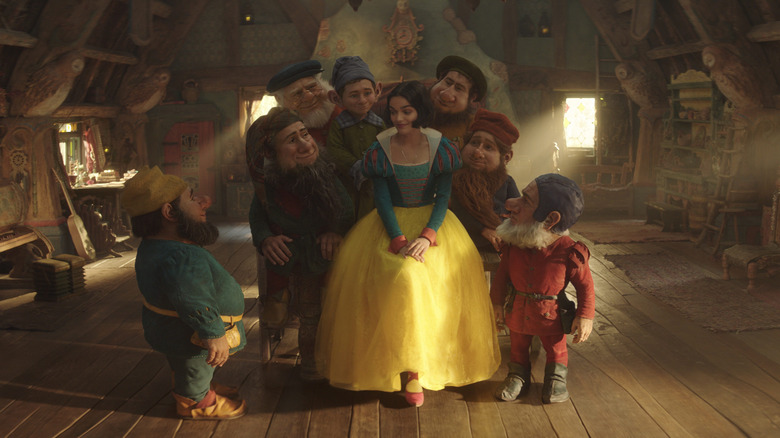 Rachel Zegler as Snow White surrounded by the seven dwarfs in Snow White (2025)