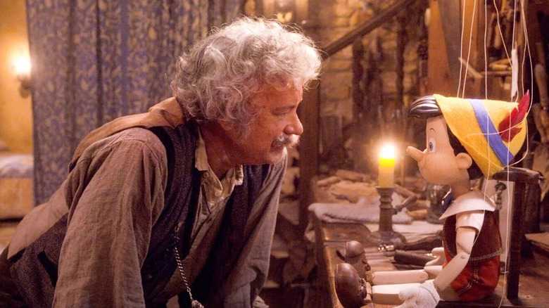 tom hanks as geppetto leaning in and looking at a pinocchio doll in pinocchio