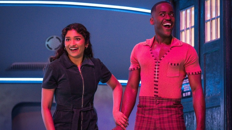 Varada Sethu as Belinda and Ncuti Gatwa as the Doctor smiling in front of the TARDIS in Doctor Who