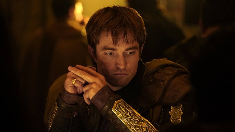 Robert Pattinson as Antinous sitting at a table in The Odyssey