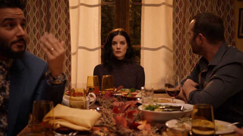 Jaimie Alexander como Jane Doe sentada al final de una mesa para la cena, luciendo sorprendida con Ennis Esmer como Rich y Sullivan Stapleton como Kurt en Blindspot