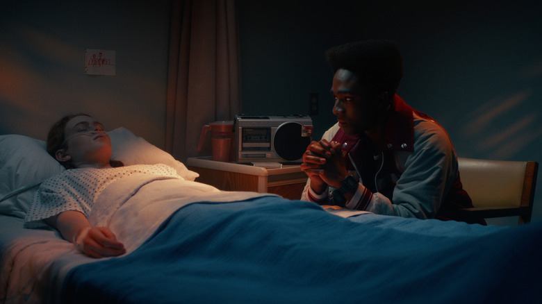 Lucas sitting by Max's hospital bed in Stranger Things