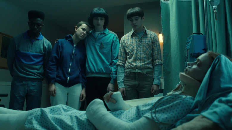 Lucas, Eleven, Mike, and Will looking at Max in a hospital in Stranger Things