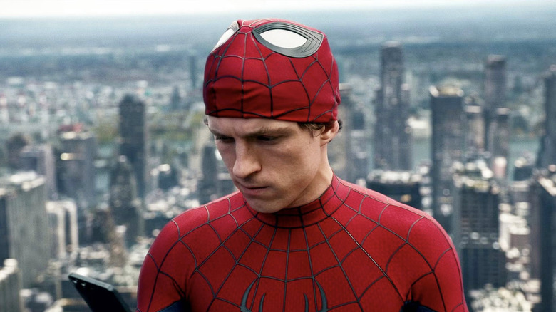 Tom Holland as Peter Parker looking at his phone atop a skyscraper in Spider-Man: Brand New Day