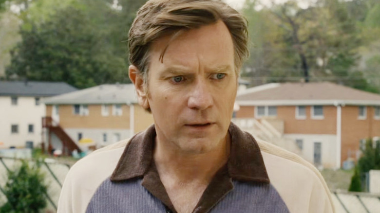 Anne Hathaway as Greg Platt looking down at something in concern in The End of Oak Street