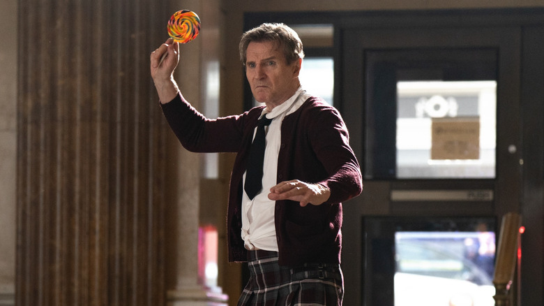 Liam Neeson as Frank Drebin Jr. using a lollipop as a weapon in The Naked Gun (2025)