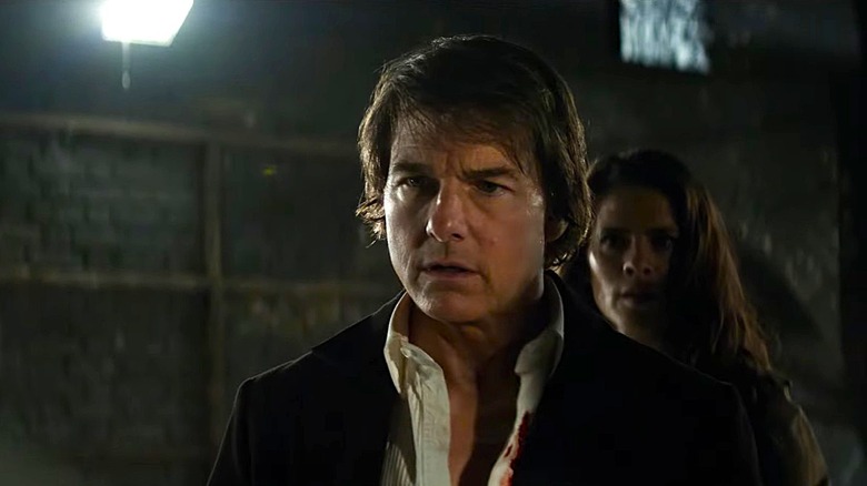 Ethan Hunt (Tom Cruise) stands in front of Grace (Hayley Atwell), and each look concerned at something to their right