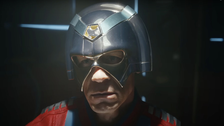 Peacemaker (John Cena) in full superhero gear being interviewed by Maxwell Lord (Sean Gunn) and the Justice Gang in Peacemaker season 2