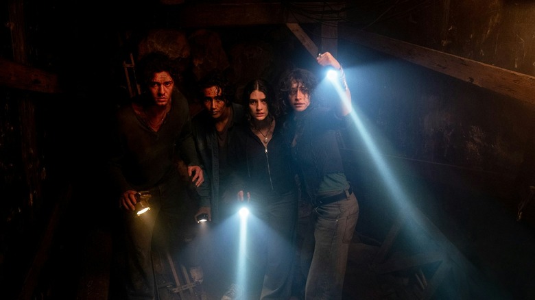 Abe, Max, Clover, and Nina holding up their flashlights walking through the mines in Until Dawn