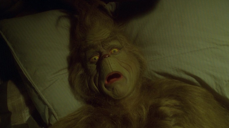Jim Carrey's Grinch is seen in closeup as he lies in bed in How the Grinch Stole Christmas