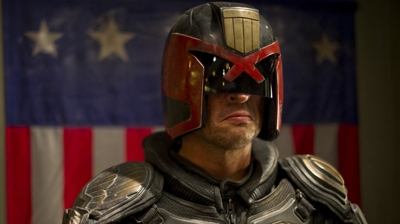 Karl Urban as Judge Dredd standing in front of the flag in Dredd