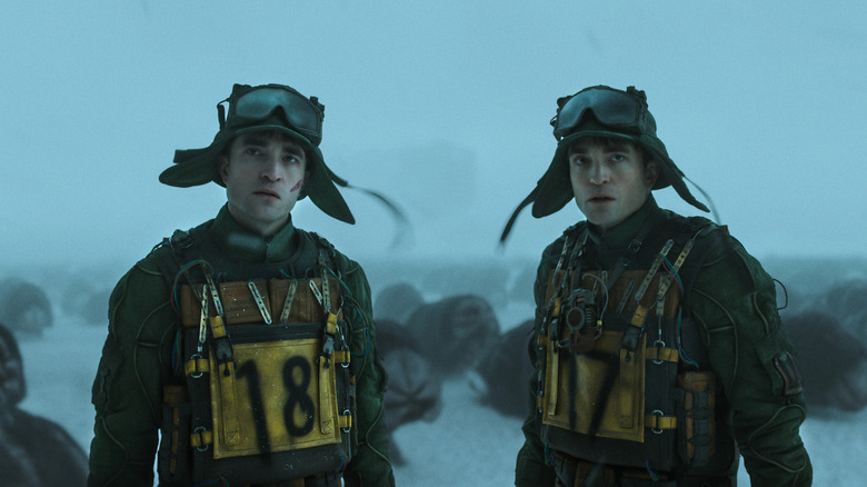 Robert Pattinson as clones Mickey 17 and Mickey 18 standing outside on a wintry planet in Mickey 17
