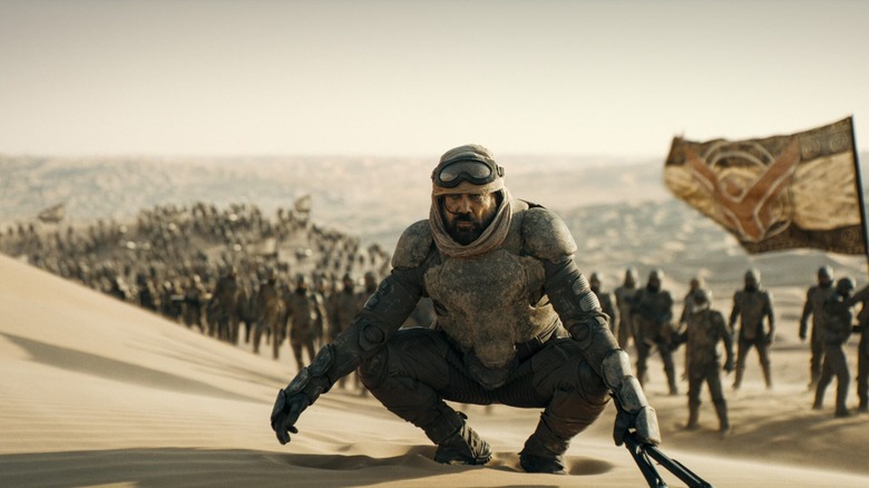 Stilgar squatting in the sand with an army behind him in Dune: Part Two.