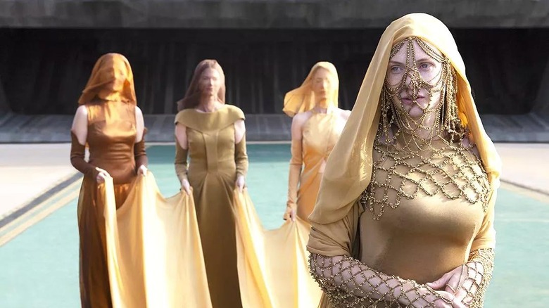 Jessica walking in a gold dress carried by three other women in "Dune" (2021)