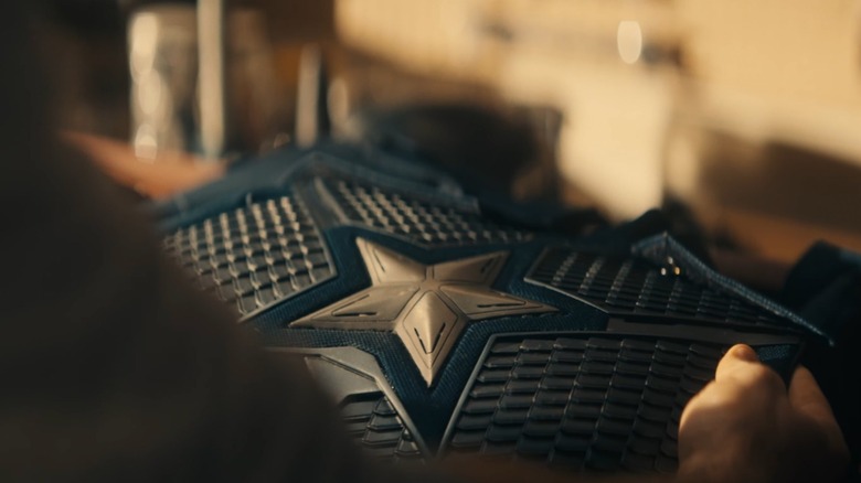 Chris Evans as Steve Rogers holding up his Captain America suit in Avengers: Doomsday