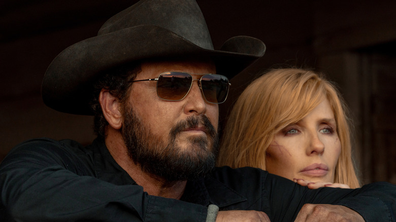 Cole Hauser's Rip Wheeler looks off into the distance wearing shades next to Kelly Reilly's Beth Dutton in Dutton Ranch