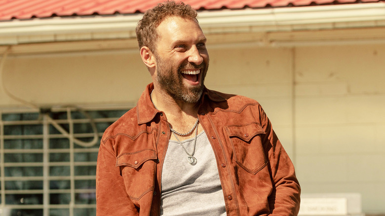 Jai Courtney's Rob-Will Jackson smiles as he stands outside in Dutton Ranch