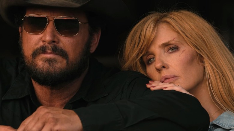 Cole Hauser's Rip Wheeler looks off into the distance wearing shades next to Kelly Reilly's Beth Dutton in Dutton Ranch