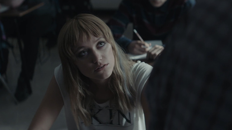 Cindy de Maika Monroe regarde quelqu'un qui se profile au-dessus de son bureau dans Flashback