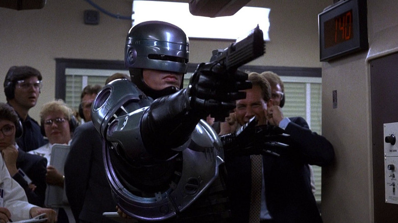RoboCop points a gun at in a shooting range as onlookers watch