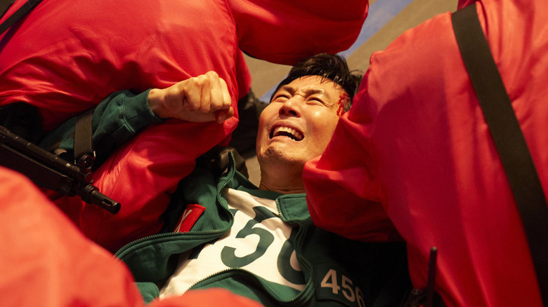 Lee Jung-jae as Seong Gi-hun dragged away by the guards on Squid Game