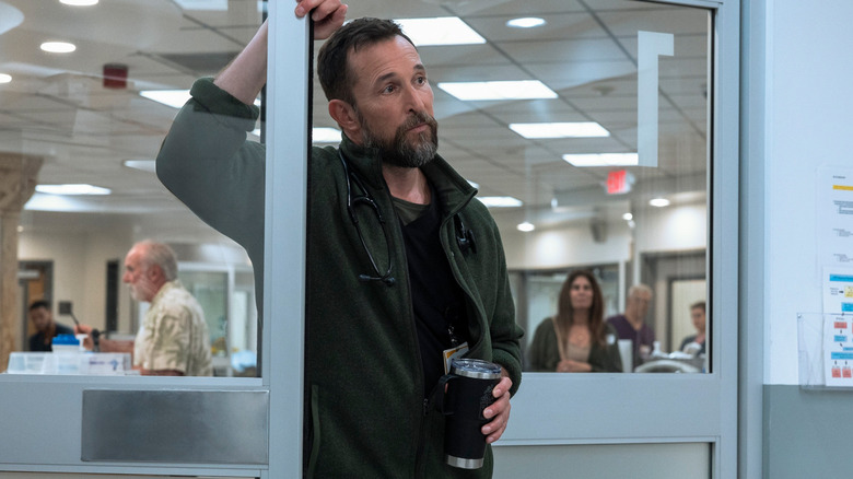 Le Dr Michael Robinavitch de Noah Wyle s'appuie contre un cadre de porte tout en tenant un verre au Pitt