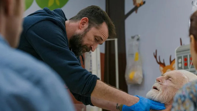 Noah Wyle's Dr. Michael Robinavitch controleert de pols van Joshua Spencer van Madison Mason in The Pitt