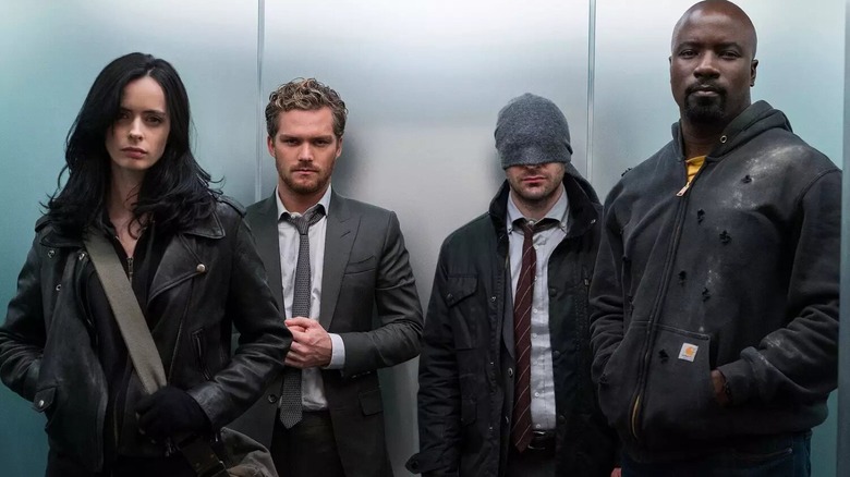 Krysten Ritter as Jessica Jones, Finn Jones as Danny Rand, Charlie Cox as Matt Murdock, and Mike Colter as Luke Cage riding an elevator together in The Defenders