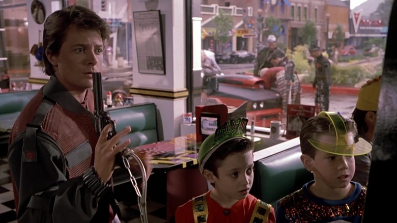 Marty McFly using an arcade gun while two boys look on in Back to the Future Part II