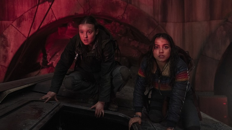 Ellie and Dina crouching on an abandoned subway car in The Last of Us season 2