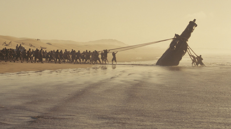 The Trojan army lifting the Trojan Horse from the sea in The Odyssey (2026)