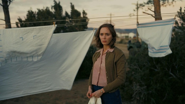 Kitty outside hanging laundry on a line looking worried in Oppenheimer