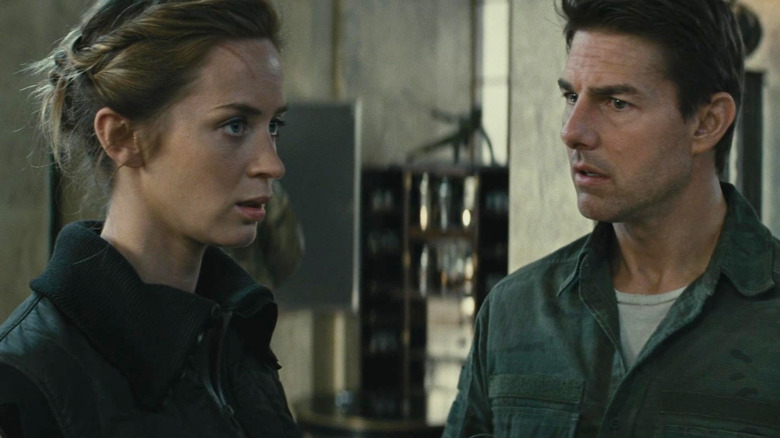 Emily Blunt as Rita Vrataski standing by Tom Cruise as William Cage in Edge of Tomorrow
