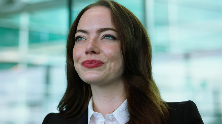 Michelle Fuller smiling and wearing a suit in Bugonia