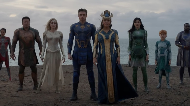 eight superheros standing in front of the ocean