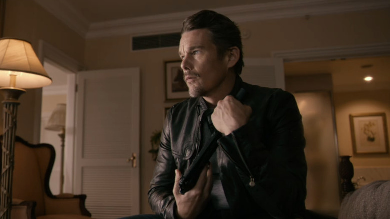 Travis Conrad d'Ethan Hawke est assis dans une chambre d'hôtel tenant son arme dans 24 heures pour vivre