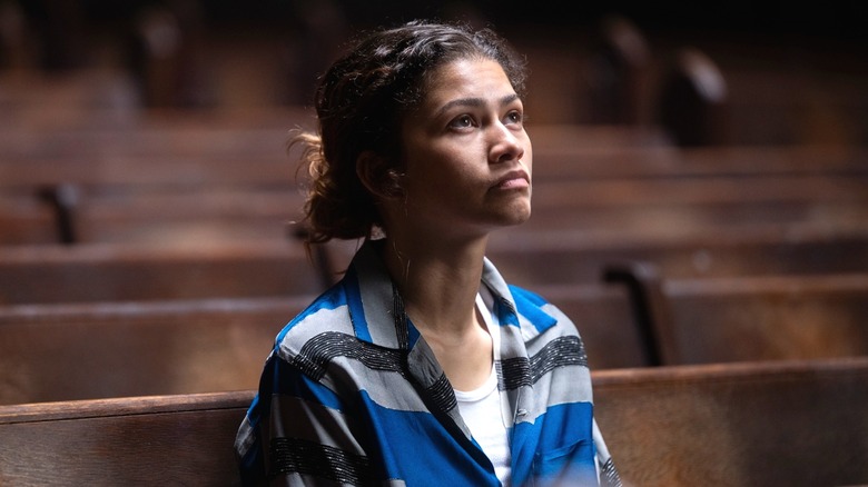 Zendaya's Rue sits down and look up at something off-screen in Euphoria