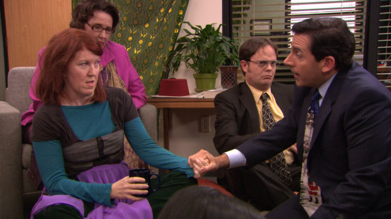 Michael (Steve Carell) holding Meredith's (Kate Flannery) hand while Phyllis (Phyllis Smith) and Dwight (Rainn Wilson) watch on The Office