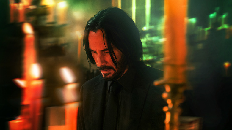 John Wick 4's Keanu Reeves kneeling at candlelit altar