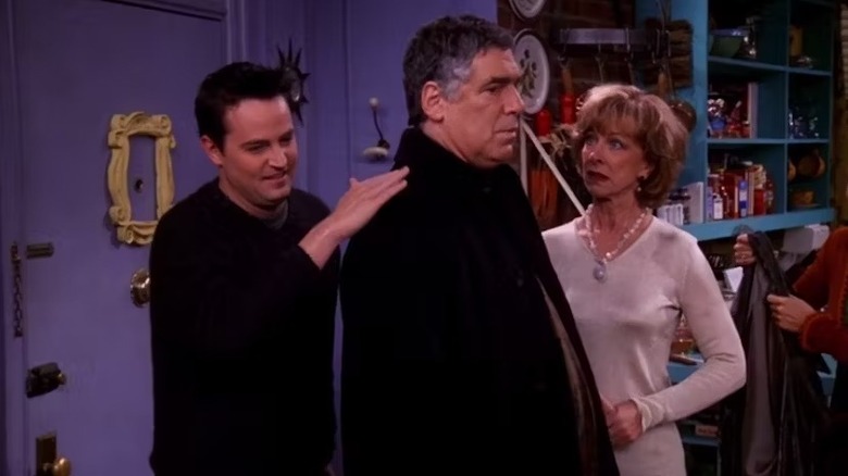 Chandler Bing (Matthew Perry) touches the back of Jack Geller (Elliott Gould) as Judy Geller (Christina Pickles) watches in Friends