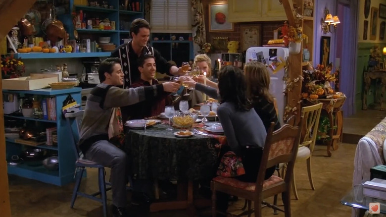 Joey Tribbiani (Matt LeBlanc), Chandler Bing (Matthew Perry), Ross Geller (David Schwimmer), Phoebe Buffay (Lisa Kudrow), Rachel Green (Jennifer Aniston), and Monica Geller (Courteney Cox) toast over sandwiches in Friends