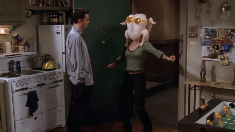 Chandler Bing (Matthew Perry) watches Monica Geller (Courteney Cox) dance with a raw turkey on her head in Friends