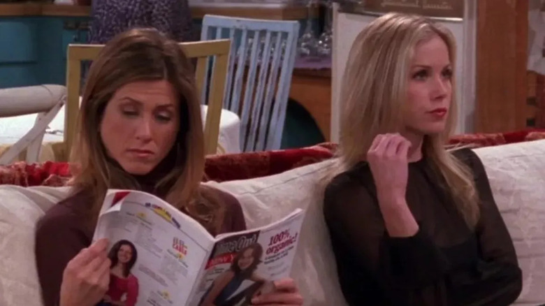 Rachel Green (Jennifer Aniston) reads a magazine seated on a couch next to Amy (Christina Applegate) in Friends