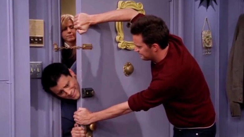Chandler Bing (Matthew Perry) closes a door on Joey Tribbiani (Matt LeBlanc), with Rachel Green (Jennifer Aniston) in the background in Friends