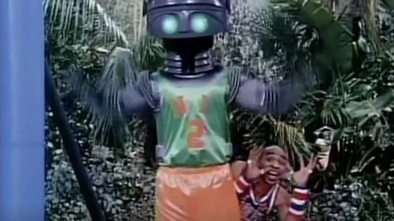A Harlem Globetrotters player stands behind a robot on a basketball court in The Harlem Globetrotters on Gilligan's Island