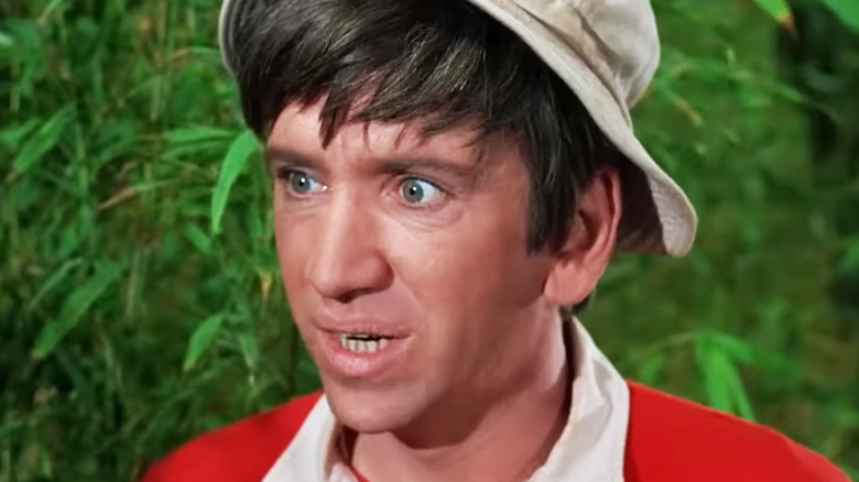 Bob Denver's Gilligan looks upset in closeup as he stands against a bush in Gilligan's Island