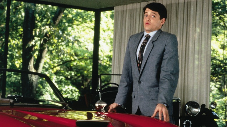 Ferris Bueller (Matthew Broderick) standing by an expensive red car in Ferris Bueller's Day Off