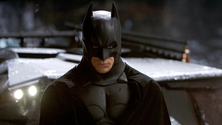 Batman (Christian Bale) glares up from the Batmobile in Batman Begins